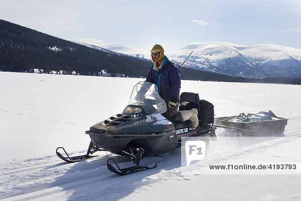 Hunter driving a snowmobile or skidoo  Yukon Territory  Canada  North America