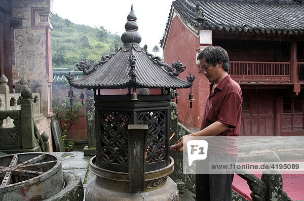 Mann entzündet Räucherstäbchen im Tempel  Weihrauchbrenner  Wudangshan Kloster  China