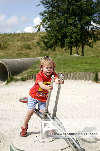 Porträt  dreijähriger Junge auf einem Spielgeräte-Bagger