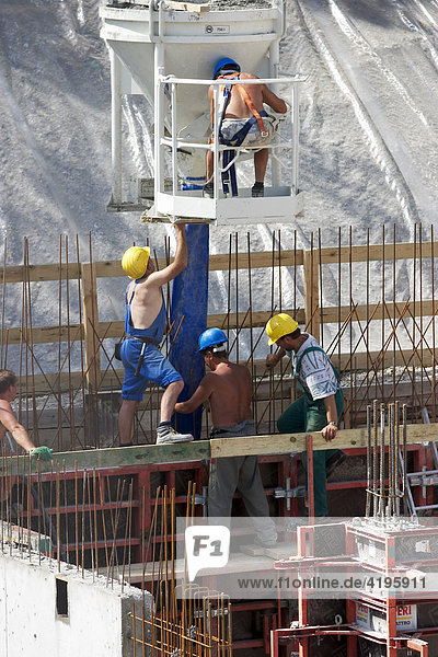 Bauarbeiter mit Betonbehälter auf einer Großbaustelle