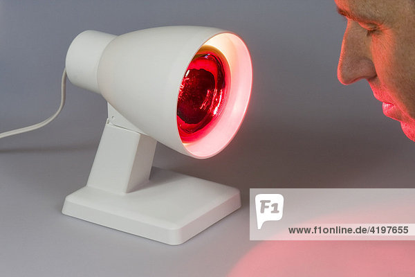 Rotlichtlampe  Infrarotlampe strahlt einem Mann ins Gesicht