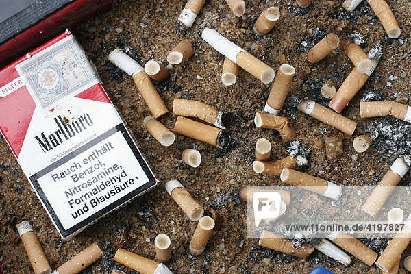 Cigarette butts in an ashtray beside a Marlboro-cigarette- packet