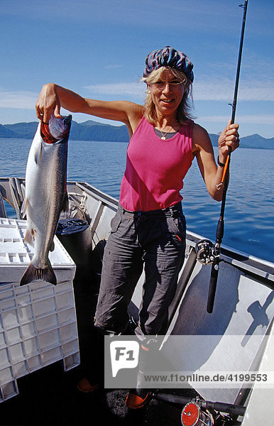 Woman catches a Coho or Silver Salmon (Oncorhynchus kisutch) in Prince William Sound  Alaska  USA