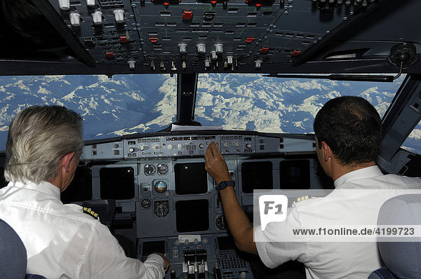 Pilots in the cockpit of an Airbus 321  in flight over the Alps