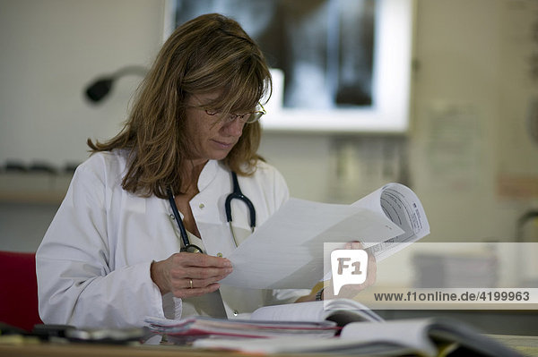 Ärztin einer Rehabilitationsklinik liest Befunde und Entlassungsberichte