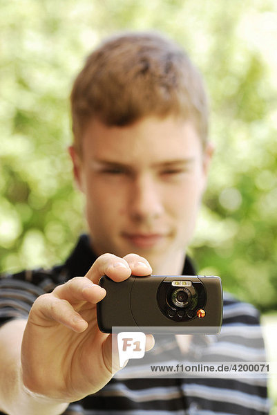 Jugendlicher fotografiert mit Handy