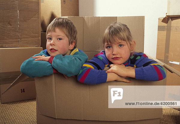 Junge und Mädchen sitzen in einem Karton