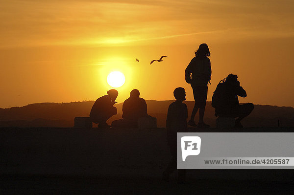 Menschen betrachten den Sonnenuntergang am Atlantik von der Promenade aus   Essaouira   Marokko   Afrika