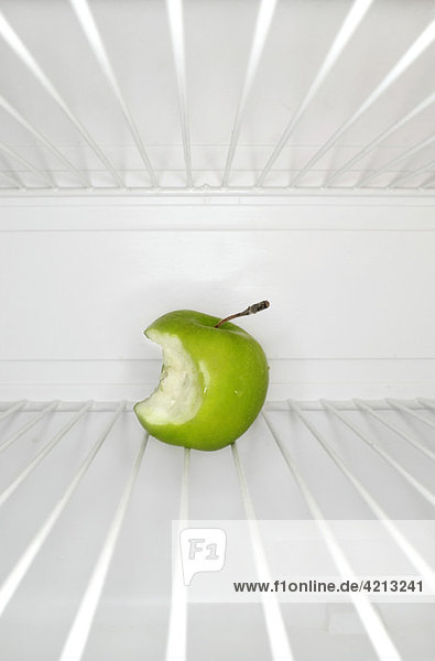 Single apple with bite mark sitting on shelf inside refrigerator
