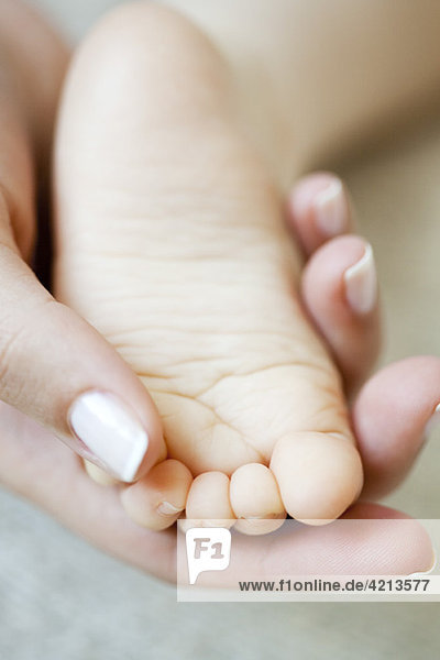 Woman's hand holding baby's foot