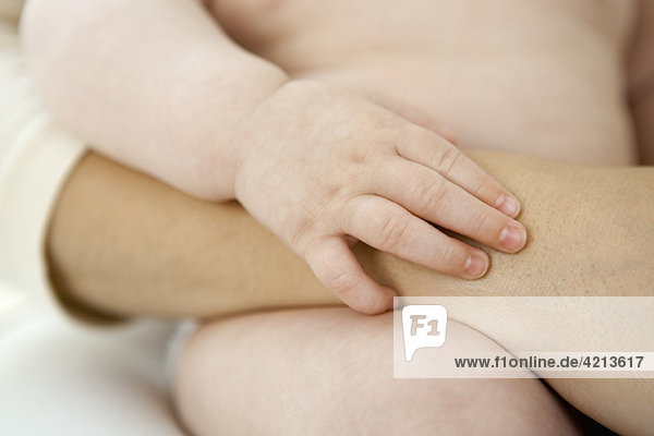 Baby holding mother's arm