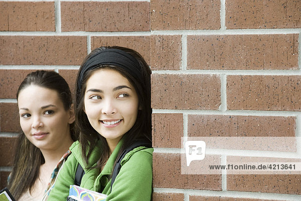 Teenage girl with friend  peeking around corner
