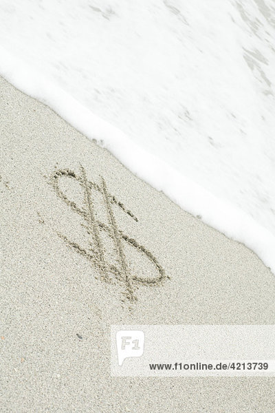 Dollarzeichen im Sand am Strand gezeichnet