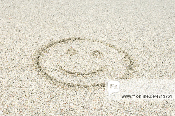 Smiley face drawn in sand at the beach