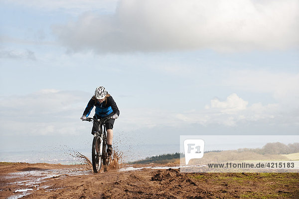 Woman riding mountain bike through mud