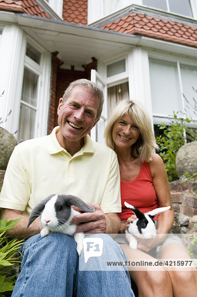 Glückliche Senioren halten Kaninchen.