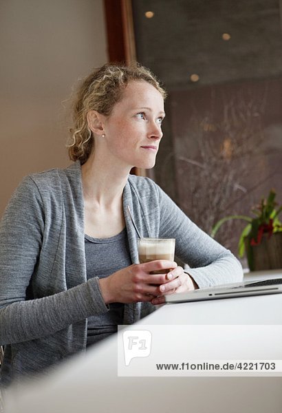 Frau im Kaffeehaus mit Blick aus dem Fenster