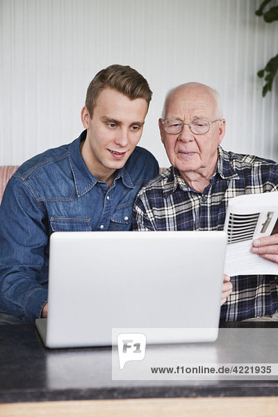 Younger guy teaching elderly man about computers