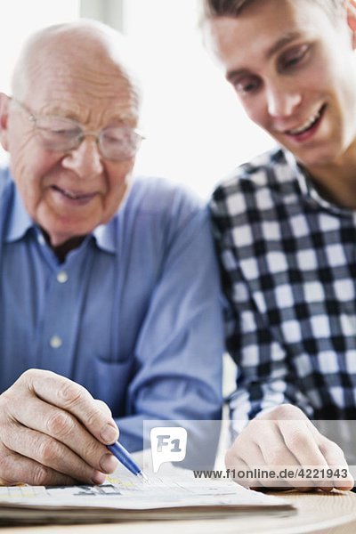 Guy and elderly man solving crossword