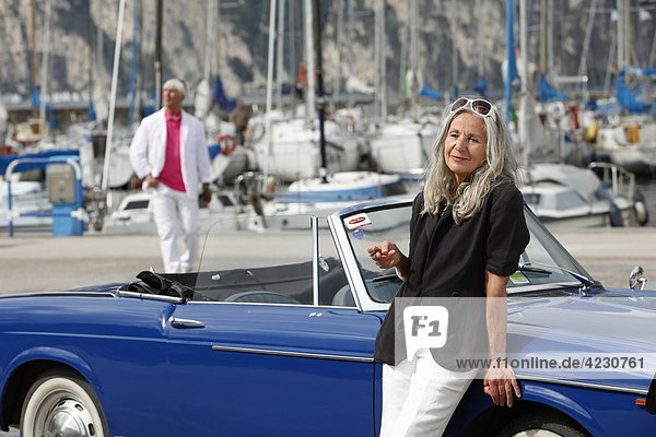 Seniorenpaar mit Cabrio am Yachthafen  Italien  Linfano