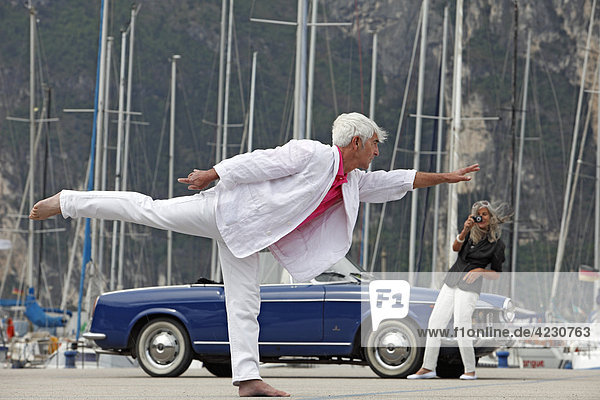 Seniorenpaar mit Cabrio am Yachthafen  Italien  Linfano