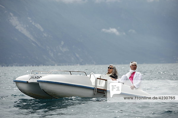 Seniorenpaar mit Tretboot vor Berglandschaft  Italien  Riva del Garda  Gardasee