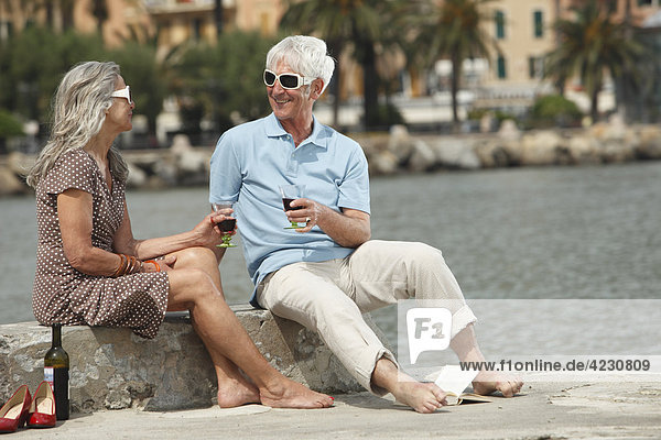 Senior couple drinking red wine by the water  Italy  Rapallo
