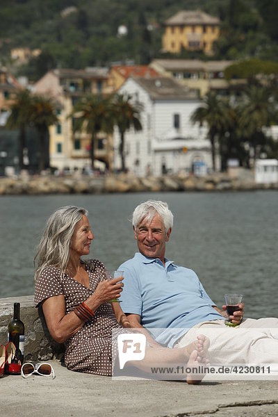 Seniorenpaar trinkt Rotwein am Wasser  Italien  Rapallo