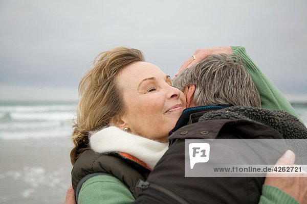 Ein reifes Paar  das sich an der Küste umarmt.