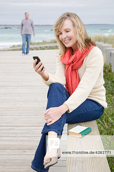 Frau an der Küste mit Smartphone