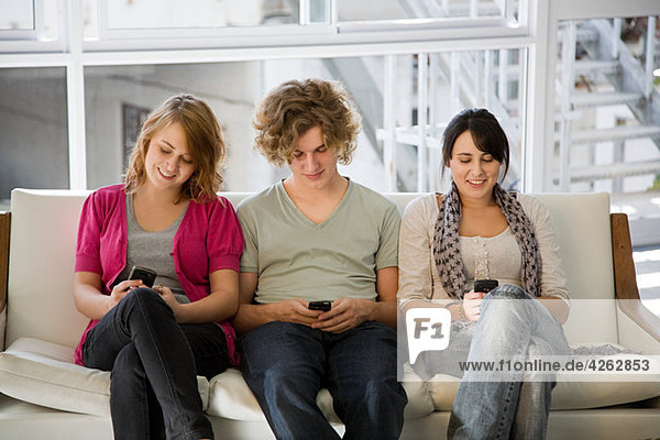 Drei Teenager texten auf Smartphones