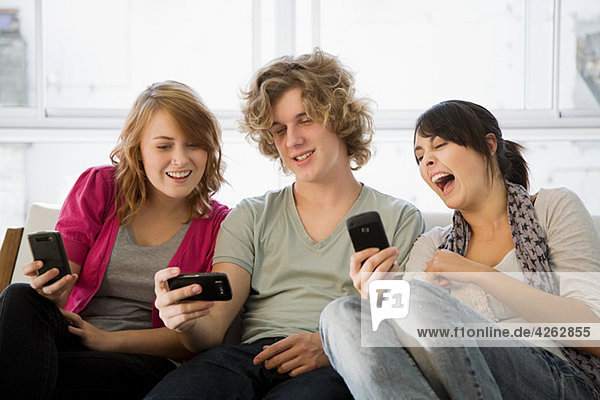 Three teenage friends looking at smartphones