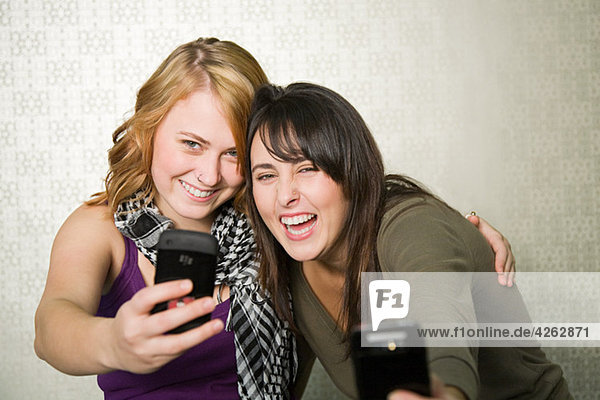 Teenage girls photographing themselves with smartphone