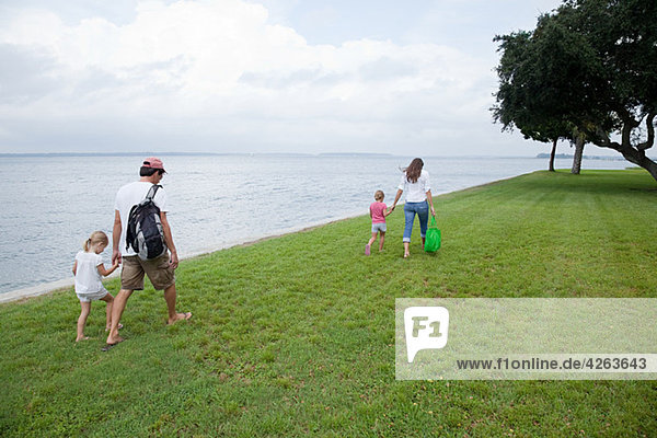 Family walking along grass by the sea