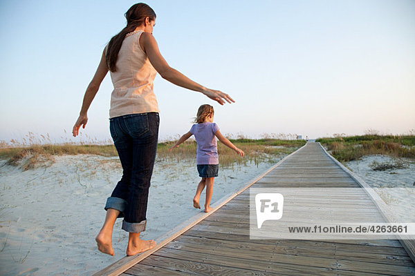Mother and daughter walking on beach walkway