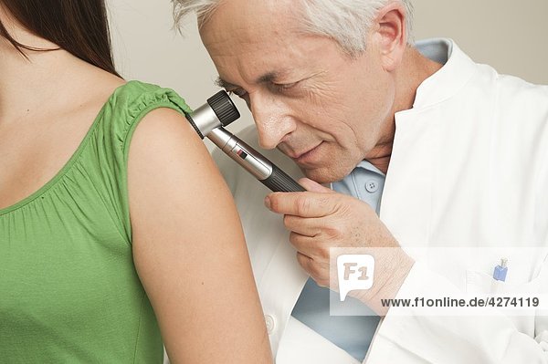 Arzt untersucht den Arm einer Patientin