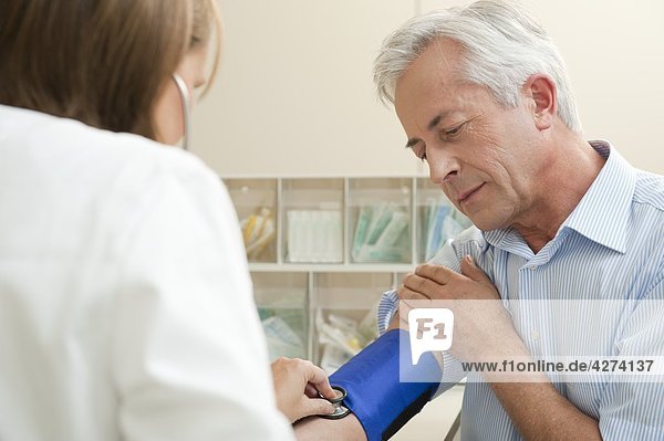 Ärztin misst bei einem Patienten den Blutdruck