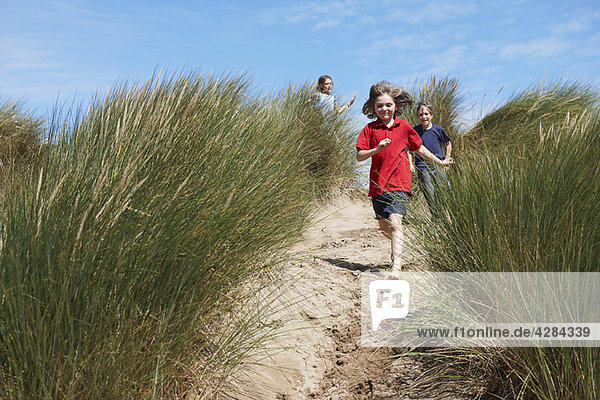 Kinder laufen durch die Sanddünen