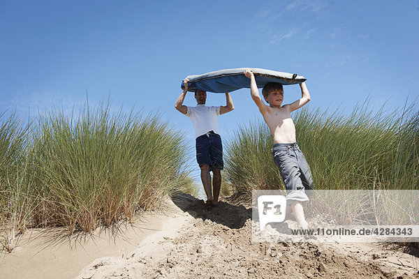 Vater und Sohn tragendes Surfbrett