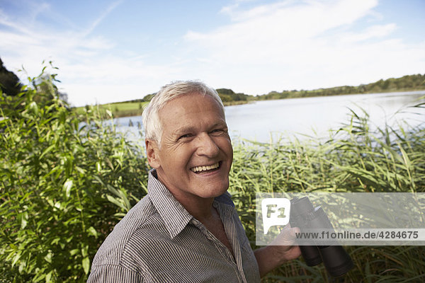 Senior Mann mit Fernglas vor dem See