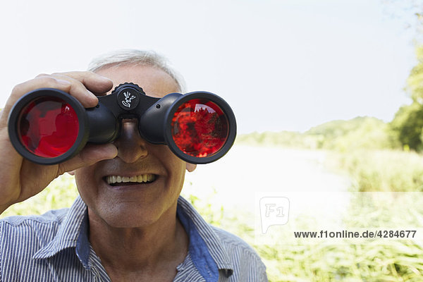 Älterer Mann  der durch das Feldglas schaut