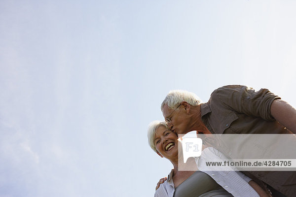 Senior Mann küsst Frau auf Wange