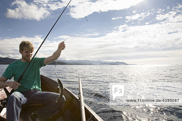 Mann beim Fischen auf einem Holzboot