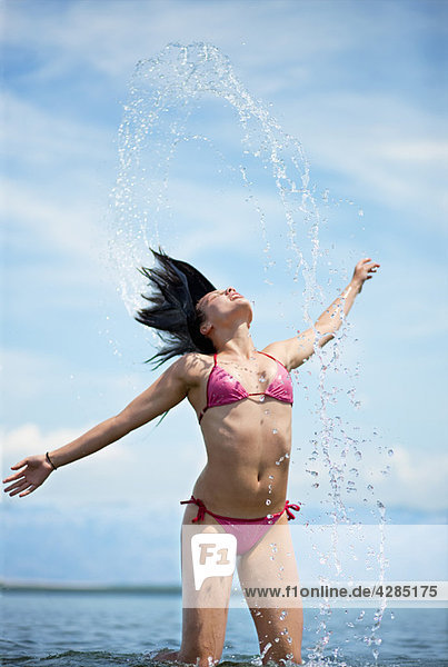 Frau spritzt Wasser am Strand