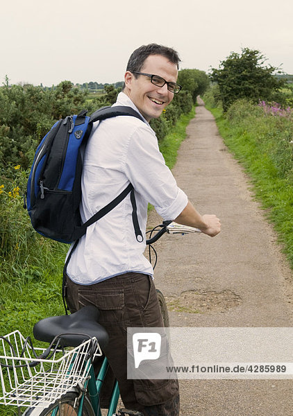 Happy man prepares to bicycle in country