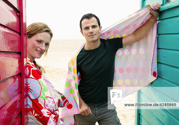Paar mit Handtüchern entspannen bei Strandhütten