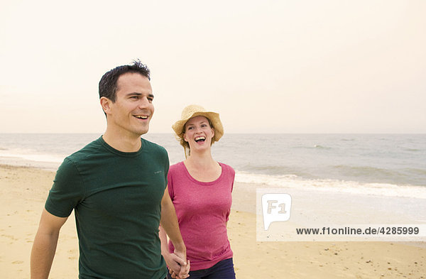 Ein glückliches Paar geht am Strand spazieren.