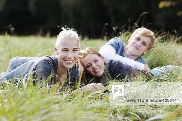 Drei junge Menschen  die im Gras liegen