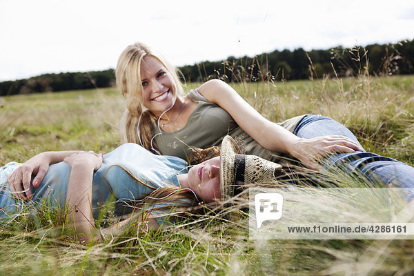 Two young women laying in grass