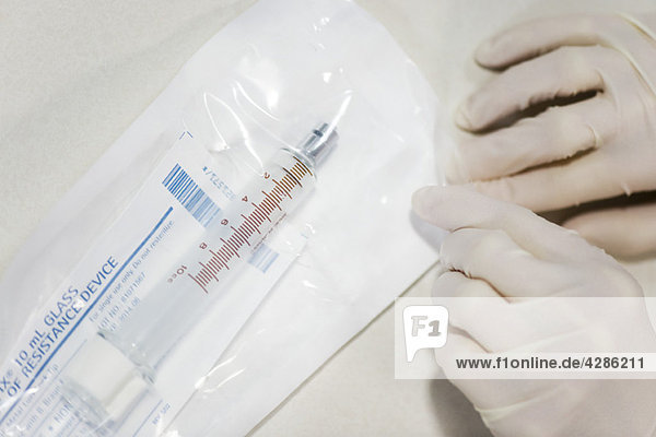 Healthcare worker opening sterile package containing medical syringe